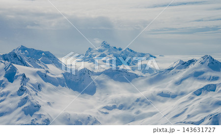 Snow-covered Mount Elbrus and surrounding Caucasus peaks with cloud-filled valleys under soft daylight 143631727