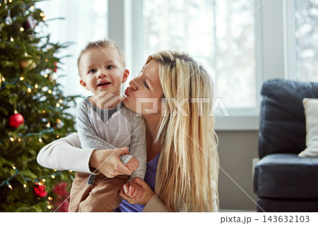 Love, child and woman kiss for christmas, tree and laugh for bonding celebration together. Smile, trust for baby and family sit on floor, motherhood happiness and festive hugs for toddler at home Love, child and woman kiss for christmas, tree and laugh for bonding celebration together. Smile, trust for baby and family sit on floor, motherhood happiness and festive hugs for toddler at home 143632103