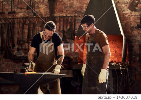 Men, blacksmith and metal teamwork in workshop for manufacturing steel, welding or fire. Male people, production and collaboration for restoration project in warehouse as handyman, skills or repair Men, blacksmith and metal teamwork in workshop for manufacturing steel, welding or fire. Male people, production and collaboration for restoration project in warehouse as handyman, skills or repair 143637019