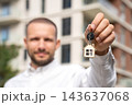 Closeup Of Real Estate Agent Offering Apartment Keys With House Keychain Outside Residential Building. New Apartment, Property Sales, Rental And Realtor Services. 143637068