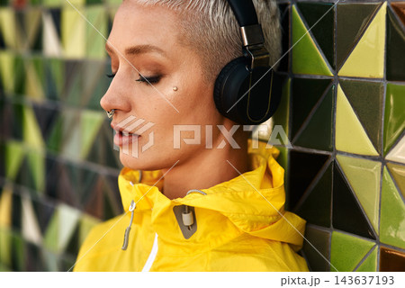 Fashion, woman and headphones at wall for streetwear, memories and calm in city. Female student, music and mosaic tiles in New York for streaming, song and cyberpunk aesthetic with accessories Fashion, woman and headphones at wall for streetwear, memories and calm in city. Female student, music and mosaic tiles in New York for streaming, song and cyberpunk aesthetic with accessories 143637193