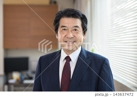 オフィスの窓際で微笑む60代男性 オフィスの窓際で微笑む60代男性 143637472