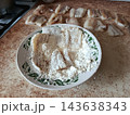Raw fish fillets are being coated in a plate of white flour, a classic step in preparing seafood for frying or baking, ensuring a crispy crust for a delicious dish 143638343