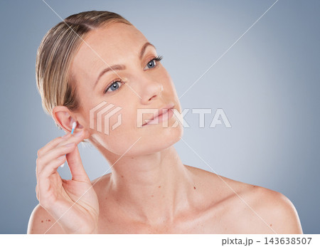 Woman, cleaning and ear for hygiene in studio for personal self care, grooming and daily routine for wellness or health. Girl, thinking and isolated on gray background with cotton bud for swab earwax Woman, cleaning and ear for hygiene in studio for personal self care, grooming and daily routine for wellness or health. Girl, thinking and isolated on gray background with cotton bud for swab earwax 143638507