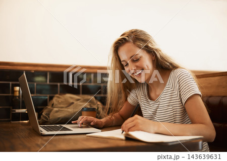 Woman, happy and writing at cafe with laptop as university student for elearning or online education. Female learner, smile and satisfied with studying or revision and research for college exams 143639631