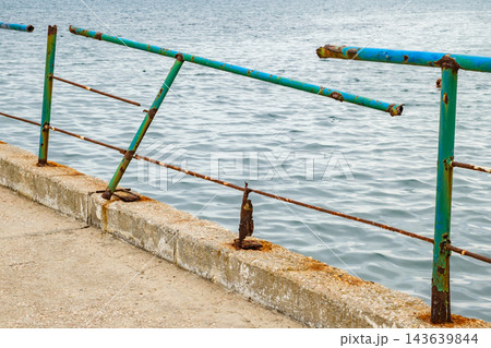 stone pier in sea with old rusty railings stone pier in sea with old rusty railings 143639844