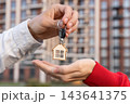 Closeup Of Real Estate Agent Handing Keys With House Keychain To Female Homeowner Outside Apartment Building. Home Purchase, Mortgage And Property Sale Concept. 143641375