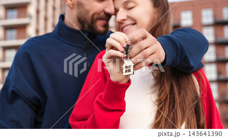 Closeup Happy Couple Embracing And Holding Keys With House Keychain Outside Apartment Building. First Home Purchase, Mortgage, Homeownership And Shared Achievement Concept. 143641390