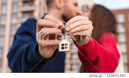 Closeup Couple Kissing And Holding Keys With House Keychain Outside Apartment Building. First Home Purchase, Mortgage, Homeownership And Shared Achievement Concept. 143641392