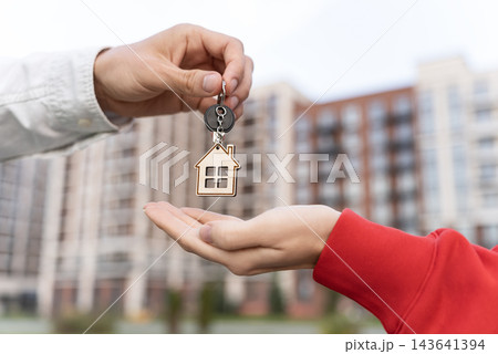 Closeup Of Woman Receiving Keys With House Keychain Outside Apartment Building. Mortgage Financing, Home Loan And Becoming A Homeowner Concept.  143641394