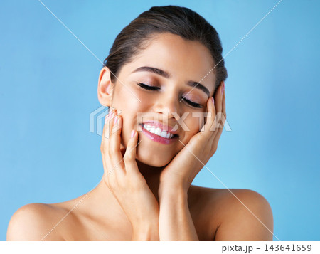 Happy woman, skincare and hands in studio for wellness, beauty and make up on blue background. Dermatology, eyes closed and female person with smile for skin glow, luxury and spa or salon treatment 143641659