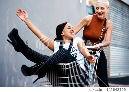 Friends, bonding and shopping cart in outdoor for play, funny and laughing together in city for freedom. Women, town and adventure in trolley for comedy, humor and crazy happiness in urban on weekend 143642596