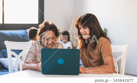 Senior woman learning how to use laptop from daughter in living room Senior woman learning how to use laptop from daughter in living room 143642877