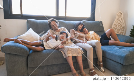 Relaxed multigenerational family watching TV on sofa at home Relaxed multigenerational family watching TV on sofa at home 143642896