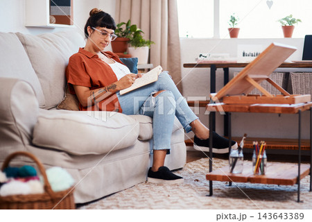 Woman, drawing and creative with book on sofa for sketch, artistic vision for tattoo company. Female illustrator, relax and home with pencil illustration for publication, design process and comic job Woman, drawing and creative with book on sofa for sketch, artistic vision for tattoo company. Female illustrator, relax and home with pencil illustration for publication, design process and comic job 143643389