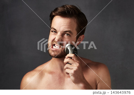 Shaver, rough or portrait of man with beard or hair removal for skincare tools, face or cosmetics in studio. Uncomfortable, pain or person on grey background for beauty, facial treatment or wellness 143643976
