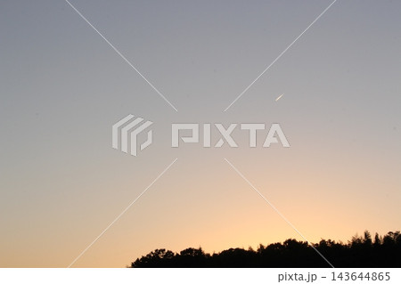 薄暮の空にひと筋流れる光と夕焼け 143644865