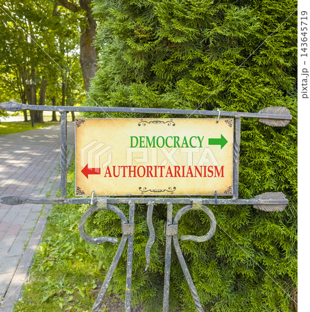 Democracy or authoritarianism symbol. Concept words Democracy Authoritarianism on beautiful information road sign. Beautiful tree background. Business democracy authoritarianism concept. Copy space Democracy or authoritarianism symbol. Concept words Democracy Authoritarianism on beautiful information road sign. Beautiful tree background. Business democracy authoritarianism concept. Copy space 143645719