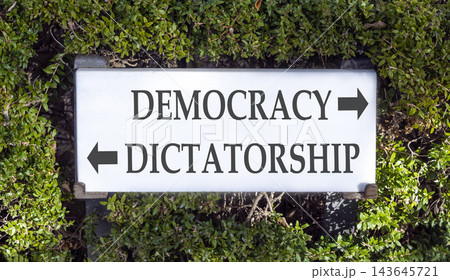 Democracy or dictatorship words symbol. Concept words Democracy Dictatorship on beautiful white sign plate. Beautiful green leaf background. Business democracy dictatorship concept. Copy space Democracy or dictatorship words symbol. Concept words Democracy Dictatorship on beautiful white sign plate. Beautiful green leaf background. Business democracy dictatorship concept. Copy space 143645721