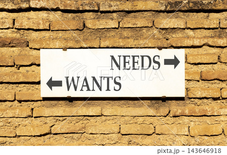 Needs instead wants words symbol. Concept words Needs Wants on beautiful white sign plate. Beautiful brick wall background. Business psychology needs or wants concept. Copy space. 143646918