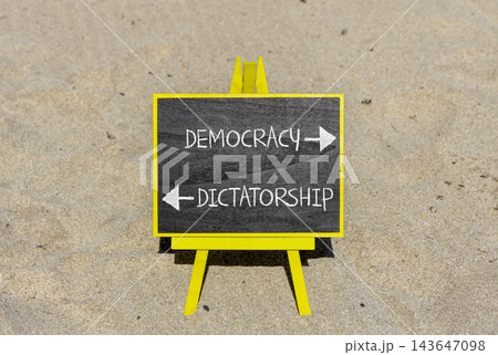 Democracy or dictatorship words symbol. Concept words Democracy Dictatorship on beautiful yellow blackboard. Beautiful sand beach background. Business democracy dictatorship concept. Copy space Democracy or dictatorship words symbol. Concept words Democracy Dictatorship on beautiful yellow blackboard. Beautiful sand beach background. Business democracy dictatorship concept. Copy space 143647098