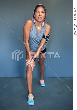 Fitness, stretching and woman with headphones in lunge for listening to music, streaming audio and radio. Sports, sweating and person warm up for training, exercise and workout on wall background 143647465