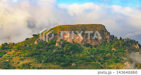 Sunlit highland plateau rises above drifting clouds with rugged cliffs and lush green slopes Sunlit highland plateau rises above drifting clouds with rugged cliffs and lush green slopes 143648860