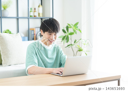 リビングでパソコンを使う若い男性 リビングでパソコンを使う若い男性 143651693