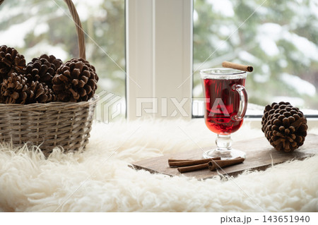 Red hot drink with cinnamon sticks by snowy window 143651940