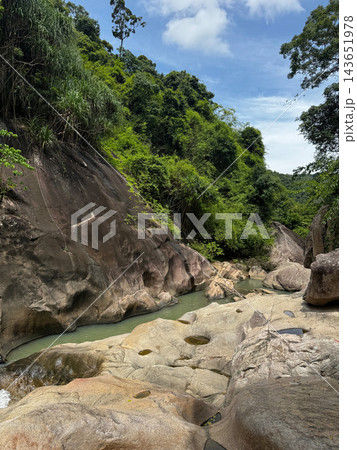 Rocky tropical stream flowing through a lush green jungle gorge 143651978
