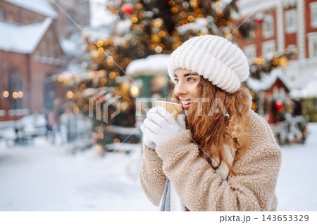 Beautiful woman playing with snow on winter street. Fashion young woman in the winter park. 143653329