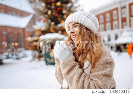 Beautiful woman playing with snow on winter street. Fashion young woman in the winter park. 143653330