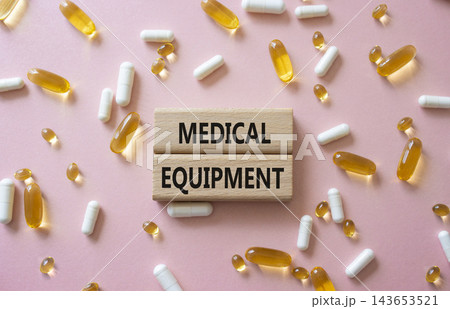 MEDICAL EQUIPMENT symbol. Concept word MEDICAL EQUIPMENT on wooden blocks. Beautiful pink background with pills. Medicine and MEDICAL EQUIPMENT. Copy space 143653521