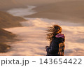 Woman watching sunrise above mountain valley 143654422