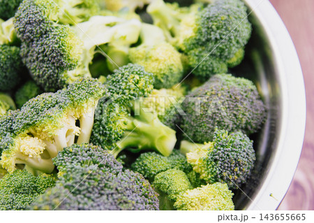 Close up of fresh raw green broccoli florets washed in stainless steel bowl for cooking healthy vegetarian meal background stock photo Close up of fresh raw green broccoli florets washed in stainless steel bowl for cooking healthy vegetarian meal background stock photo 143655665