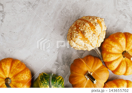 Top view of assorted mini decorative pumpkins and bumpy gourds on grey marble surface with copy space for autumn harvest or Halloween party concept 143655702