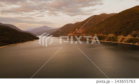 Scenic aerial landscape of Zhinvali reservoir surrounded by green mountain slopes under hazy sky during evening sunset in Georgia Scenic aerial landscape of Zhinvali reservoir surrounded by green mountain slopes under hazy sky during evening sunset in Georgia 143655763