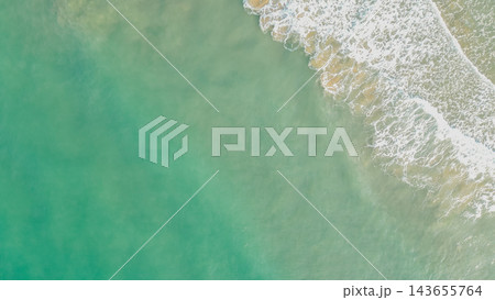 Aerial overhead photo of turquoise sea water with gentle white foam wave crashing on clear sandy shore in Greece for travel background design Aerial overhead photo of turquoise sea water with gentle white foam wave crashing on clear sandy shore in Greece for travel background design 143655764