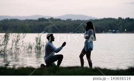 Man proposing marriage to woman by a lake at sunset 143656114