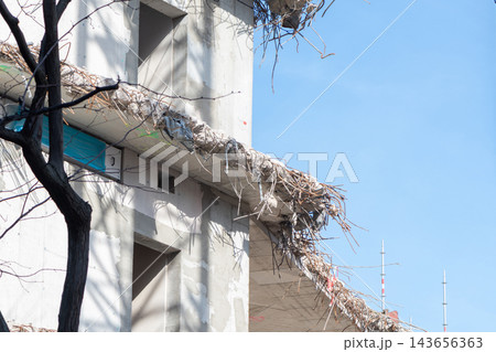 Damaged unfinished concrete building with exposed rebar against clear blue sky Damaged unfinished concrete building with exposed rebar against clear blue sky 143656363