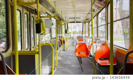 Empty tram moves along city street at sunny summer day. The calm street and passing tram capture urban life and modern public transportation in motion, emphasizing rhythm, movement and city flow 143656459