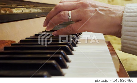 Adult female hands playing a gentle piece of classical music on a brown piano. The scene captures the movement, rhythm and elegance of performance, highlighting beauty of live instrumental play Adult female hands playing a gentle piece of classical music on a brown piano. The scene captures the movement, rhythm and elegance of performance, highlighting beauty of live instrumental play 143656460