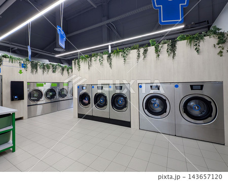 Modern self service laundromat interior with rows of washing machines and dryers Modern self service laundromat interior with rows of washing machines and dryers 143657120