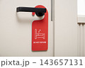Closeup of red do not disturb sign hanging on black door handle in hotel 143657131