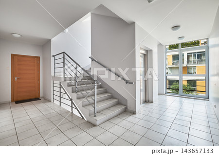 Modern apartment building staircase hall with elevator, wooden door, and panoramic window. 143657133