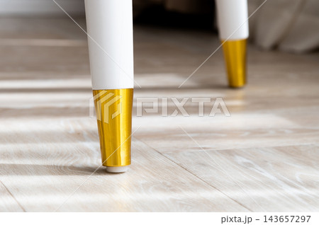 White and gold furniture leg on wooden floor White and gold furniture leg on wooden floor 143657297