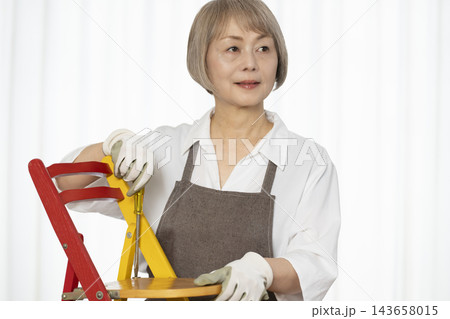 リビングで趣味のDIYで椅子を作るシニア女性 143658015
