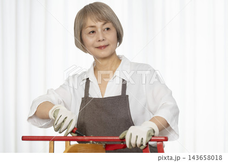 リビングで趣味のDIYで椅子を作るシニア女性 リビングで趣味のDIYで椅子を作るシニア女性 143658018