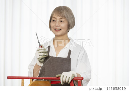 リビングで趣味のDIYで椅子を作るシニア女性 143658019