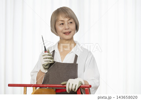 リビングで趣味のDIYで椅子を作るシニア女性 143658020